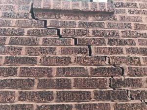 Hairline cracks and mortar deterioration showing early signs of stone foundation settlement.