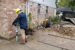 Masonry specialists resetting stones and repointing mortar during stone foundation repair.