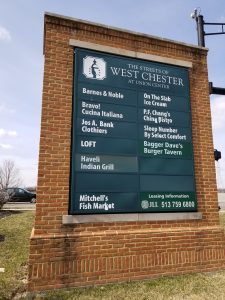 A large brick sign for The Streets of West Chester at Union Center lists businesses including Barnes & Noble, Bravo!, Jos. A. Bank, LOFT, Haveli Indian Grill, Mitchell’s Fish Market, and several restaurants.
